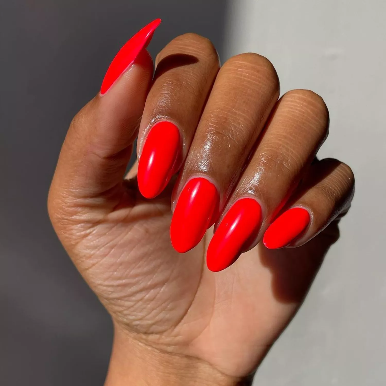 Person showing off their cherry red nails, which are oval-shaped