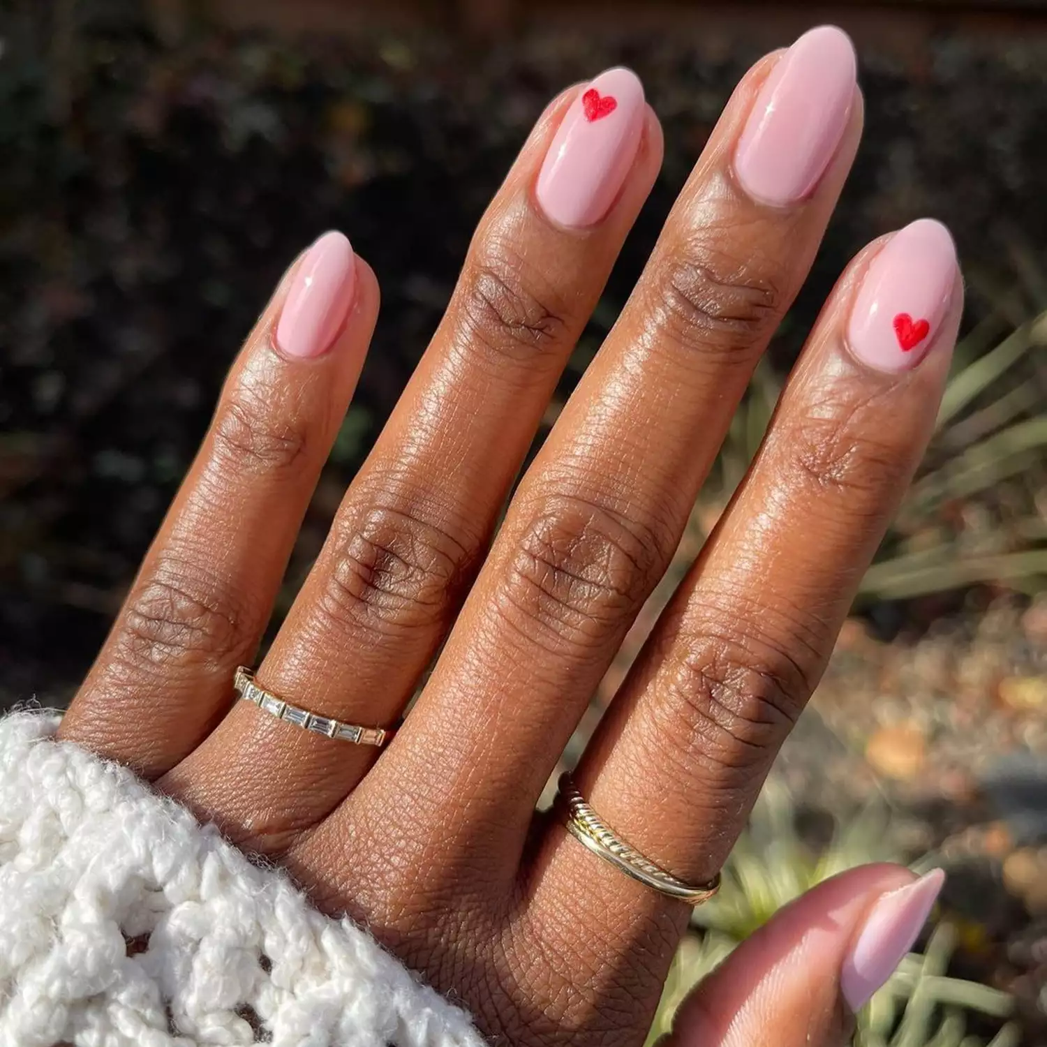 Dainty red heart accents on pinkish-nude nails