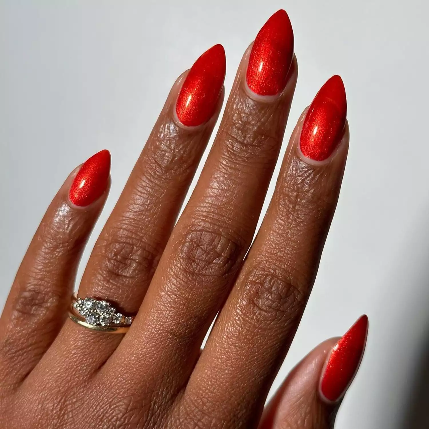 Person showing off their shiny and dimensional red nails, which are in a coffin shape