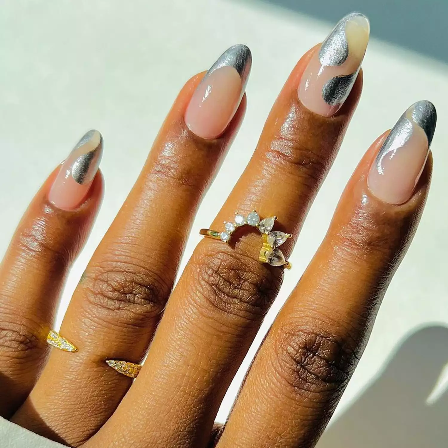 A neutral manicure with silver swirls and French tips