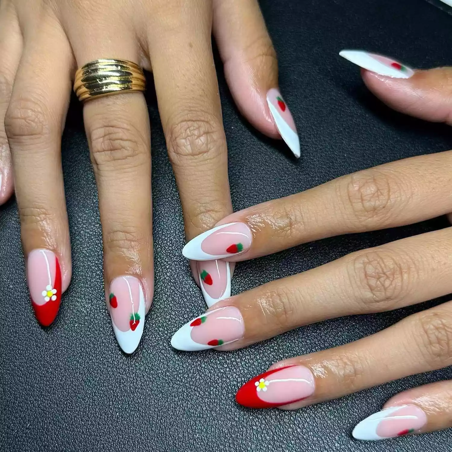 Person showing their red and white French tip nails with daisy and strawberry accents