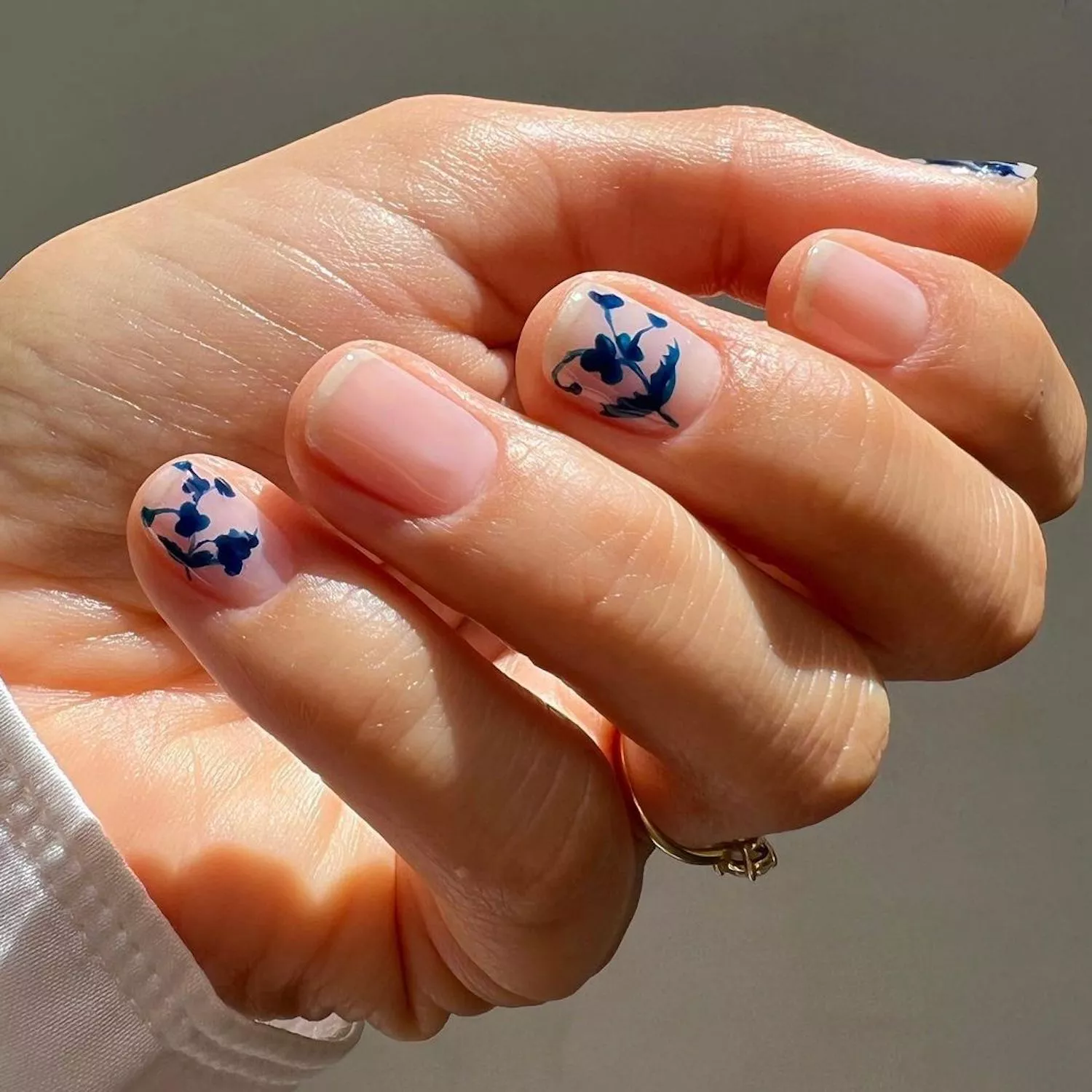 Glossy neutral nails with blue floral designs