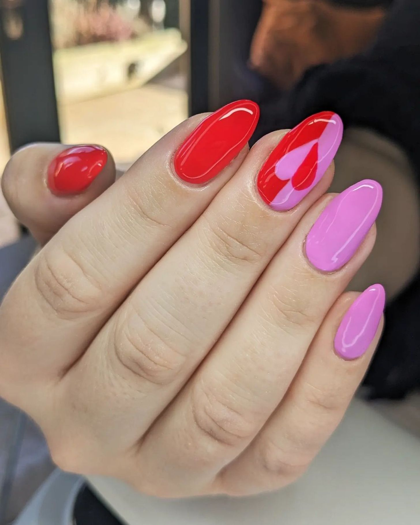 Cute red and pink nails with half-heart art on the middle finger