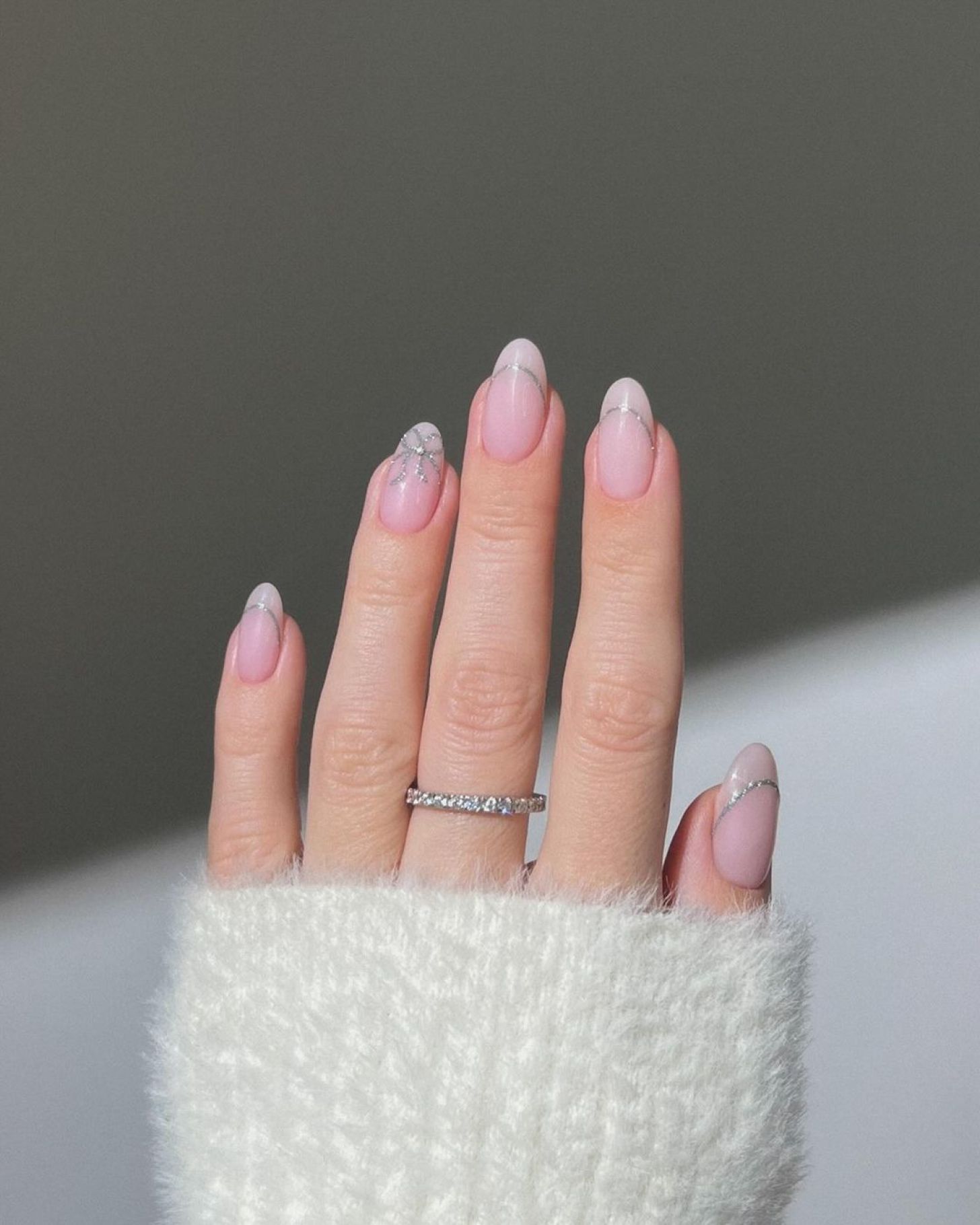 nude Valentine's Day nails with simple silver glitter designs and cute bow nail art on the French-inspired tips