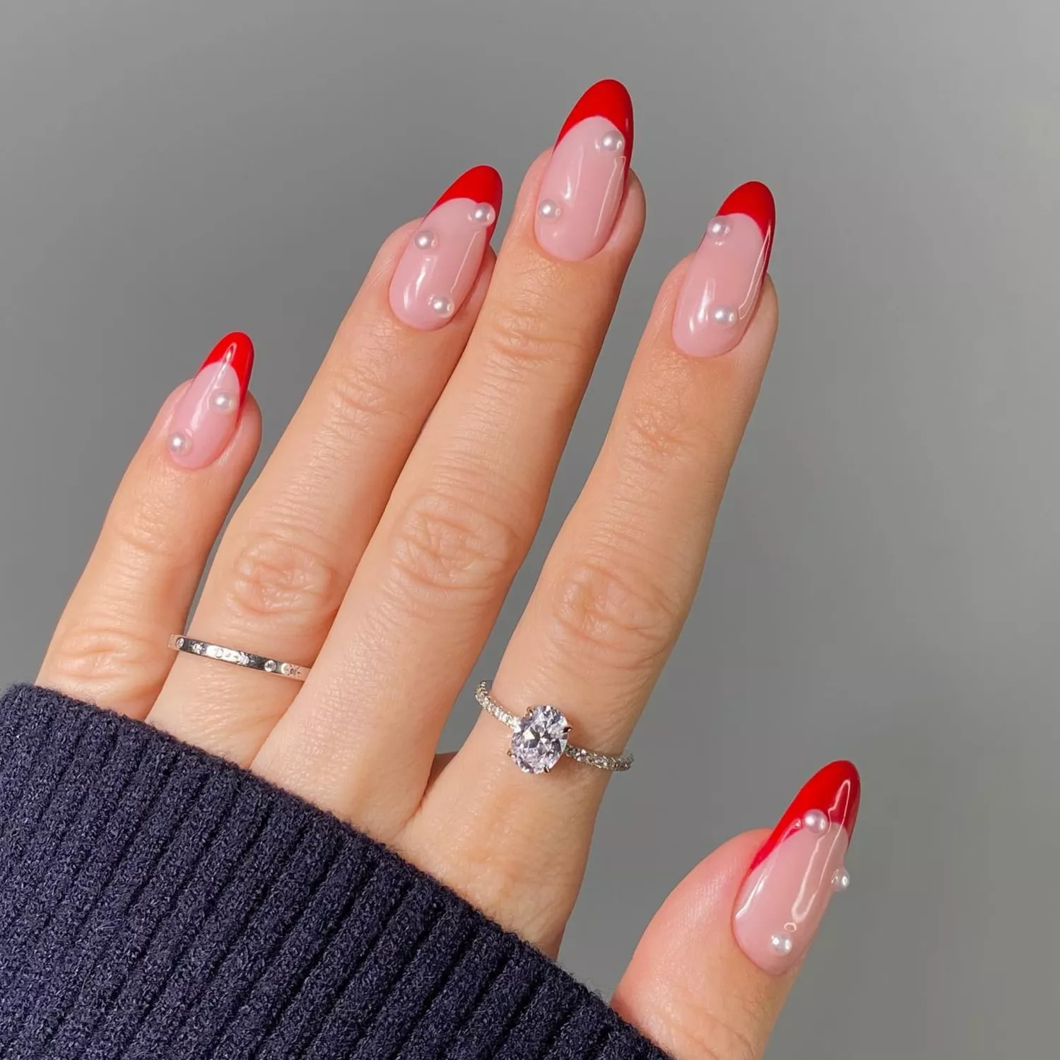 Red French manicure with pearl gemstones.