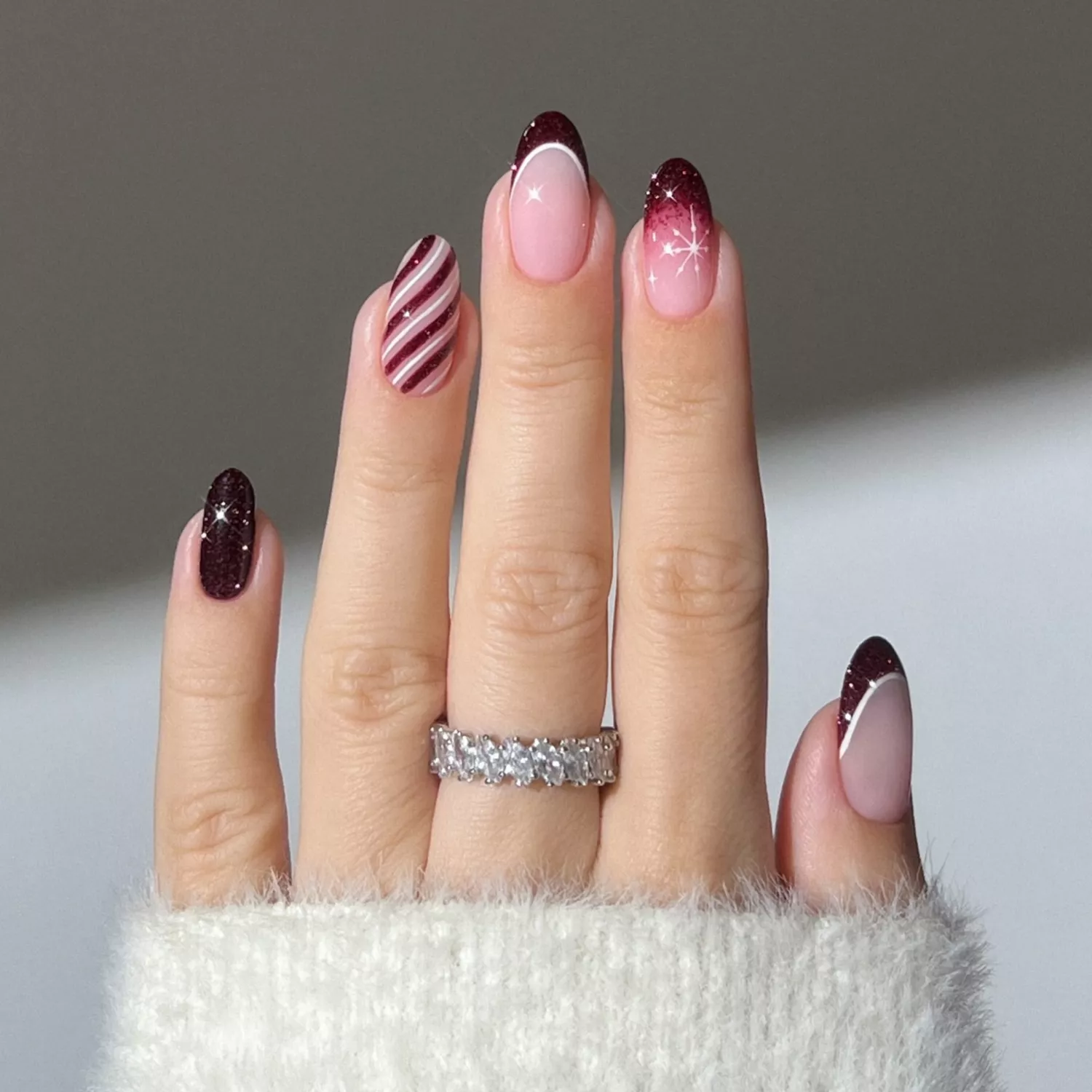 Red Christmas mismatched nails with Santa hat, snowflake, and candy cane stripe details.