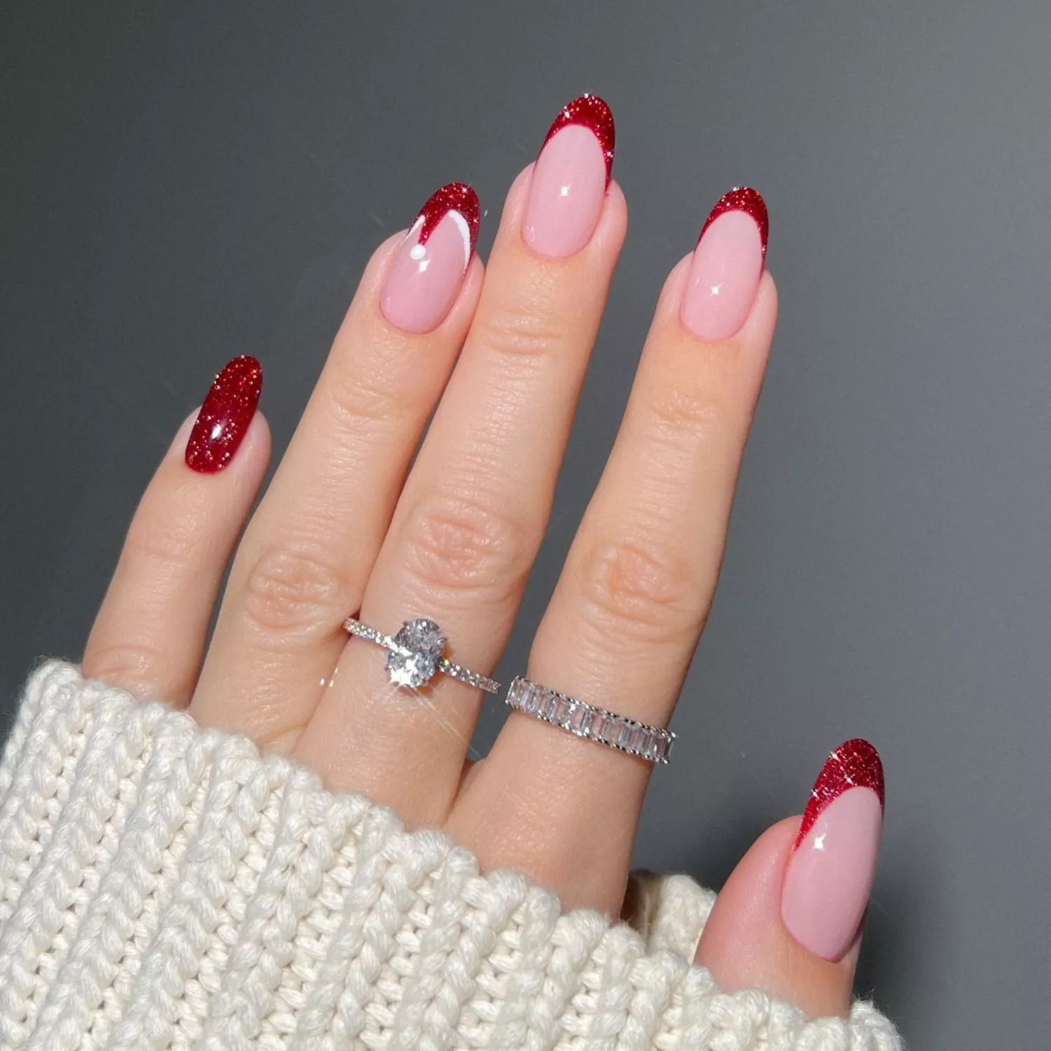 Red glitter French tips with a Santa hat puff ball detail.