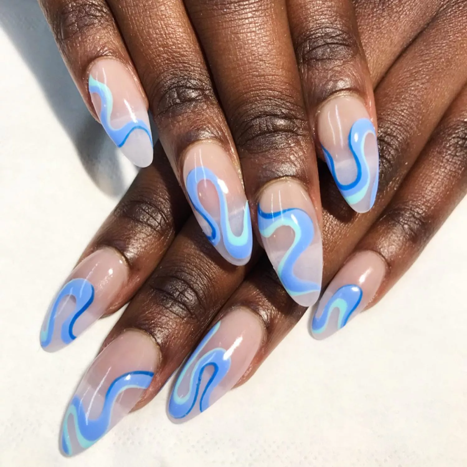 A swirly nail design featuring shades of blue